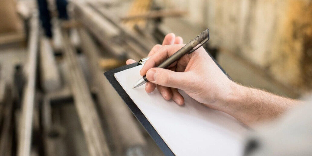 A person writing on paper with a pen.