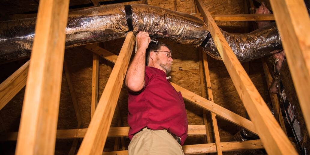 A man in red shirt holding up a pipe.